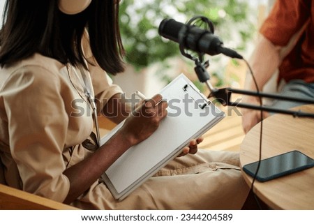 Podcaster writing down questions for her radio show