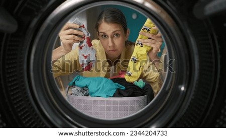 View from inside the washing machine, adult woman looking confused holding a different socks Royalty-Free Stock Photo #2344204733