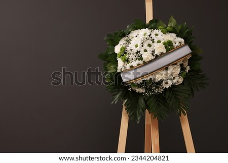Funeral wreath of flowers with ribbon on wooden stand against grey background, space for text Royalty-Free Stock Photo #2344204821