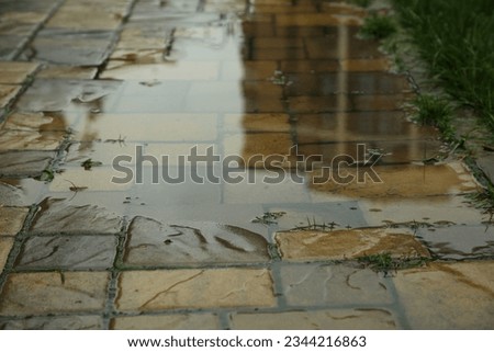 Puddle after rain on street tiles outdoors, closeup