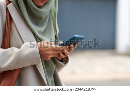 Cropped image of muslim woman answering text messages on smartphone