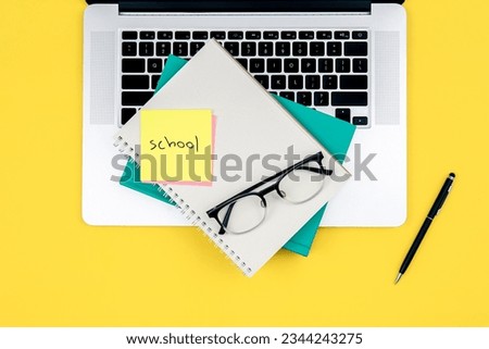 Laptop and notebooks on a yellow background, top view.