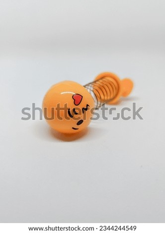 Yellow spring toy with emoticon face shape on white background