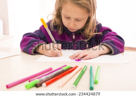 Child draws the picture. Blurred pens on the foreground