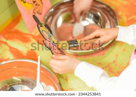 A child draws with colored sand picture. Cartoon characters. selective focus