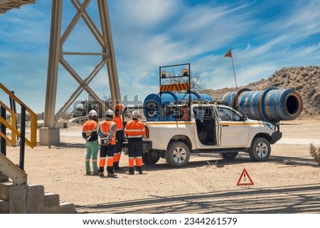 diamond mine managerial team discussing work plans behind a 4x4 vehicle on a dirt road under a bridge Royalty-Free Stock Photo #2344261579