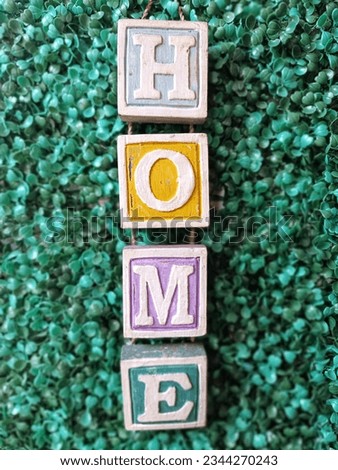 a wall hanging wood sign with the words home in front of the green grass