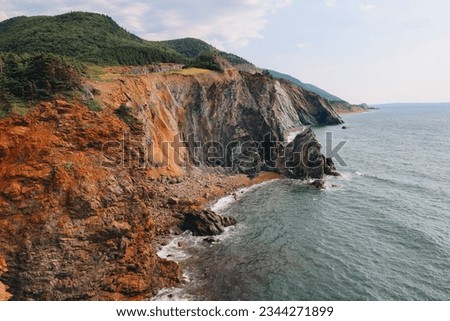 brown orange cliffs with a blue ocean. picture taken in summer on the Cabot Trail in Nova-Scotia, Canada 