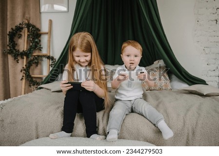 Childs watching cartoons online on phones at home alone. Children playing mobile device video game. Cute little boy, girl using smartphone. Kids sibling gen Z using parental control app on cell phone.