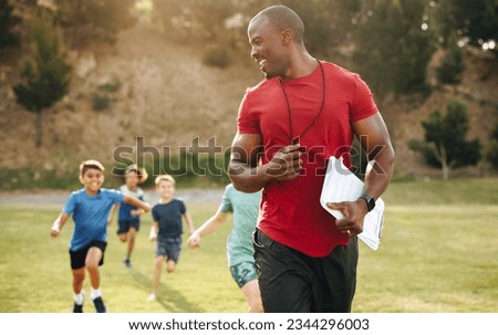 Sports trainer coaching elementary school children. Male PE teacher having a running session with group of kids in a school ground. Sports education in primary school. Royalty-Free Stock Photo #2344296003