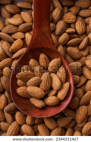 Dried almonds. Almond kernels lie in wooden spoon. Top view of nuts close-up. Advertising photography for marketplaces or online stores.