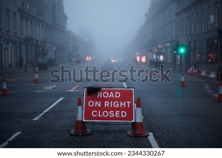 Road ahead closed sign in empty city with street lights.