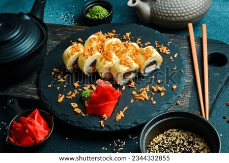 Japanese sushi with fish and cheese on a rustic dark background. Sushi rolls, nigiri, maki, pickled ginger, wasabi, soy sauce. Sushi set on a table.