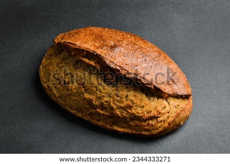 Homemade oval rye bread with flax. Fresh bread on a black background. Top view.
