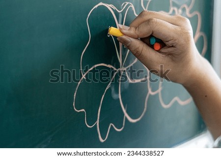 Close-up image focusing on the hand holding chalk to write on the board