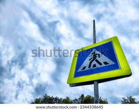 Road sign Pedestrian crossing. Blue square on yellow background with a black figure of a walking person. Traffic rules