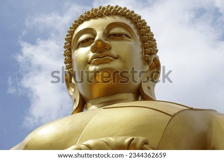 A large Buddha image, towering above the sky, with a kind and faithful face, like a picture of the heavens, seeing clouds and the sky.