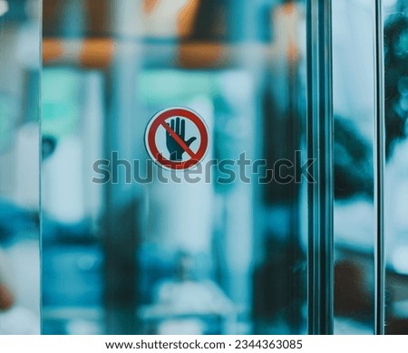 Stop hand warning icon for don't touch sign on glass door in modern public interior