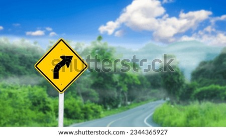 Right curve directional arrow on yellow sign on blurred road and mountains background concept of warning people driving safely                               