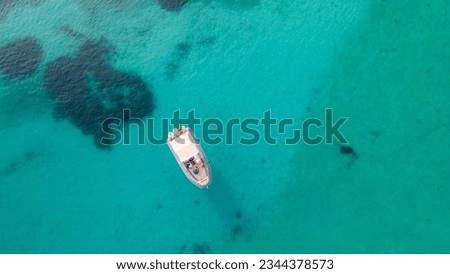 Aerial drone ultra wide photo of inflatable rib power boat anchored in the lagoon in tropical exotic bay with coral reef and deep blue sea with lot of fish. Bird eye view, water sport theme.