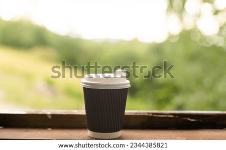 A takeaway paper cup placed on a black wooden table. This photo is suitable for use as a mockup to put your logo or design on it.