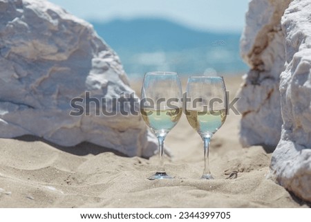 Romantic sunset dinner on the beach. Table honeymoon set for two with glasses of white wine drinks in a restaurant with sea view. Summer love, romance date on vacation concept.