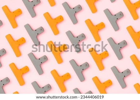  Back to school flat lay on pink background. Gray and orange binder clip flat lay on pink background.