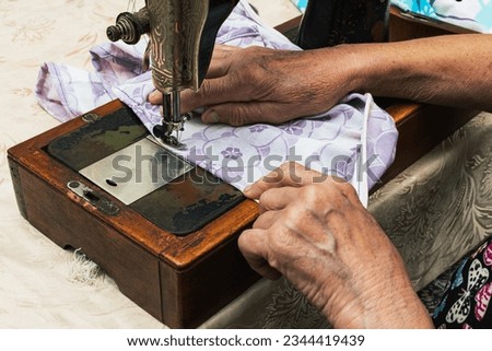 Sewing fabric at home on an old sewing machine with kind hands