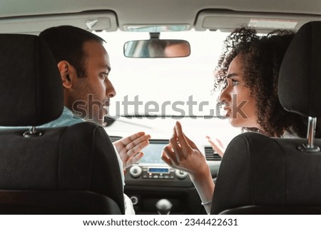 Relationship and Conflicts. Middle Eastern Spouses Engaging in a Heated Quarrel and Argument Amidst Traffic Jam in Car, Back View Perspective. Angry Man And Woman Arguing During Auto Ride Royalty-Free Stock Photo #2344422631