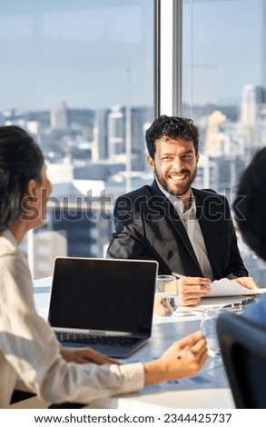 Happy busy professional young latin business man company executive working with team colleagues people discussing project in office at group meeting table in corporate boardroom. Vertical