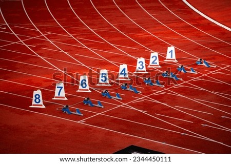 Start of sprint race. Numbers and starting blocks on the red track. Athletics stadium. Track and field photo. Starting numbers on athletics track.