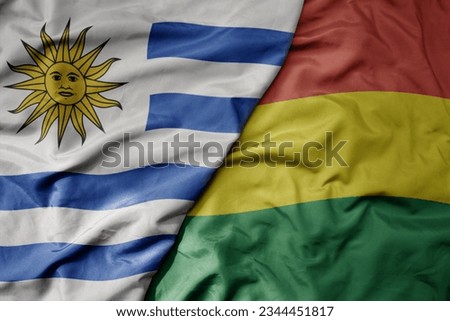 big waving realistic national colorful flag of uruguay and national flag of bolivia . macro