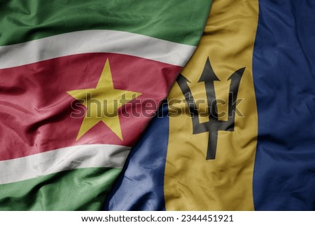 big waving realistic national colorful flag of suriname and national flag of barbados . macro