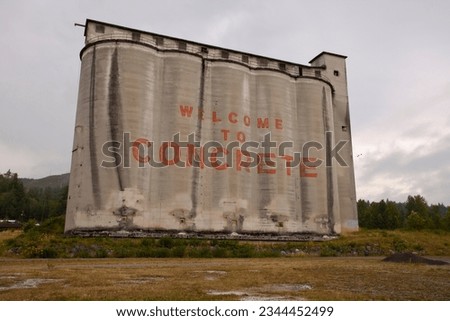 The welcome sign for the town of Concrete in Washington State is painted on a large, grey, industrial concrete elevator in the center of town.
