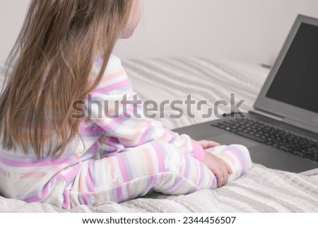 Screen kids time. Small girl looking at laptop. Enjoying kid cartoons on using laptop. Focused on watching interesting video online. Spending time.