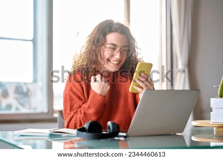 Young happy lucky woman student feeling excited winner looking at cellphone using mobile phone winning online, receiving great news or sms offer, getting new job celebrating achievement. Royalty-Free Stock Photo #2344460613