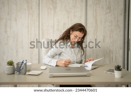 One woman female caucasian entrepreneur businesswoman or secretary sitting at her office at desk work checking paper documents contract wear shirt copy space sign contract