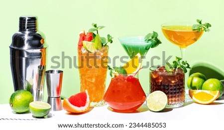 Alcoholic beverages, summer cocktail party. Multicolored low alcohol drink glasses set. Green background, hard light, shadow pattern Royalty-Free Stock Photo #2344485053