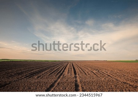 Selective blur on furrows on a Agricultural landscape near a farm, a plowed field in the countryside of Titelski, Serbia, Voivodina. The plough is a technique used in agriculture to fertilize a land. Royalty-Free Stock Photo #2344515967