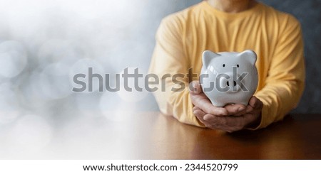 Man hand holding piggy bank on wood table, saving money wealth and financial concept, Business, finance, investment, Financial planning. Panoramic business banner with copy space.