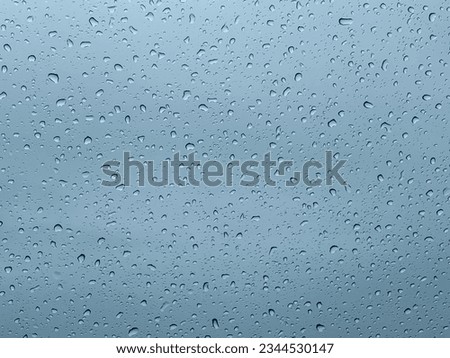 Slightly abstract light blue gray sky background for product presentations with complex lights and shadows of raindrops falling on the window glass.