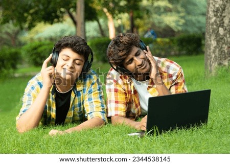 Portrait of Asian teenager friends Student listening to music with wireless earphones, using laptop. dressed in casual clothing. Teenagers lifestyle concepts