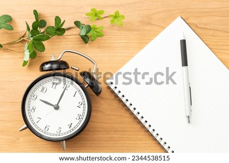 Notebook and alarm clock on the table.