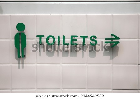 Sign indicating the way to the toilet.Sign showing the way to the bathroom.The green sign points the way to the men's restroom.