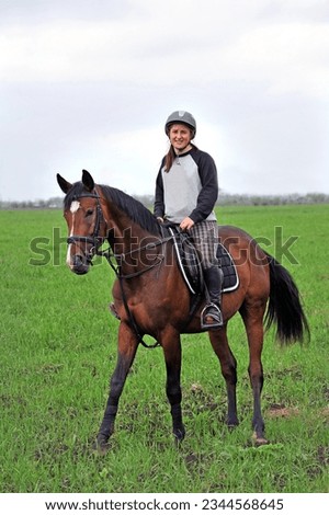 Jockey girl riding a horse in the summer on a green field