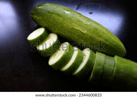 The flesh of a cucumber is crisp and mild in flavor, with a high water content that gives it a refreshing and cooling quality. It has a subtle earthy taste with a hint of sweetness, making it a popula Royalty-Free Stock Photo #2344600833