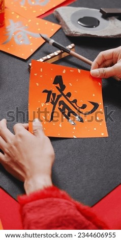 close up of asian woman finish writing spring festival couplet to celebrate Lunar new year with word meaning Dragon Royalty-Free Stock Photo #2344606955
