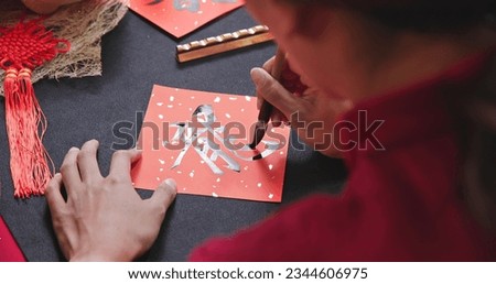 back view of asian woman write spring festival couplet to celebrate Lunar new year with word meaning Dragon Royalty-Free Stock Photo #2344606975