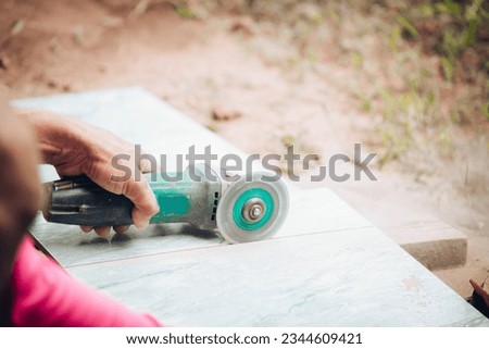 Worker cutting a tile using an angle grinder at construction site. Cutting large ceramic tiles. The worker cuts the tiles with a special tool. Quality photo. construction concept.