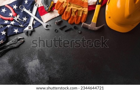 Happy Labor day concept. American flag with different construction tools on dark background.